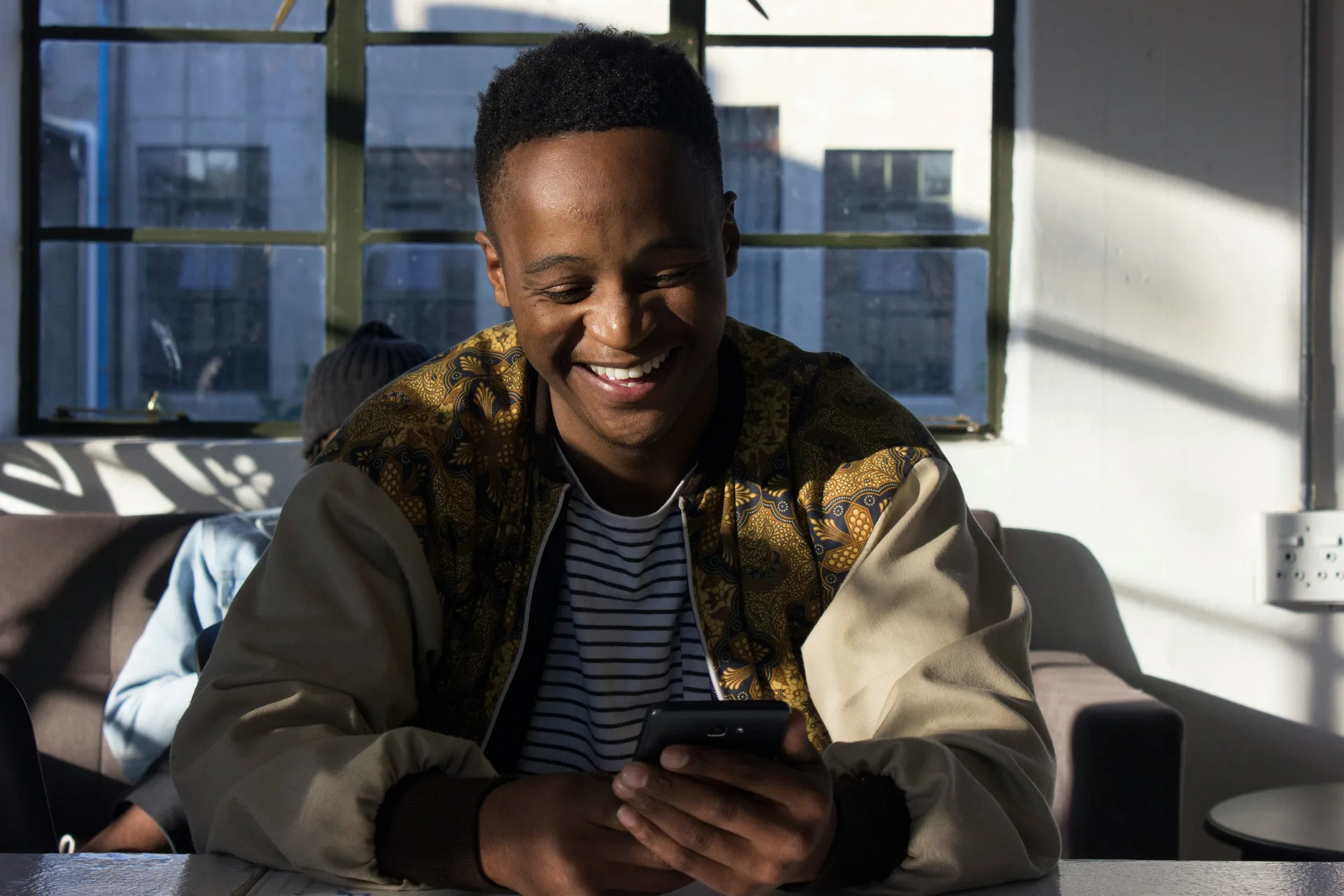Young East African professional using mobile app at café